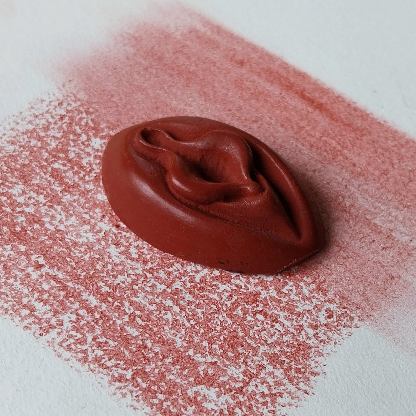 Crayon de subversion VULVA NATURALIS rouge, vue de profil. Crayon de cire, pastel gras. Dépose de couleur sur une feuille puis estompe au doigt