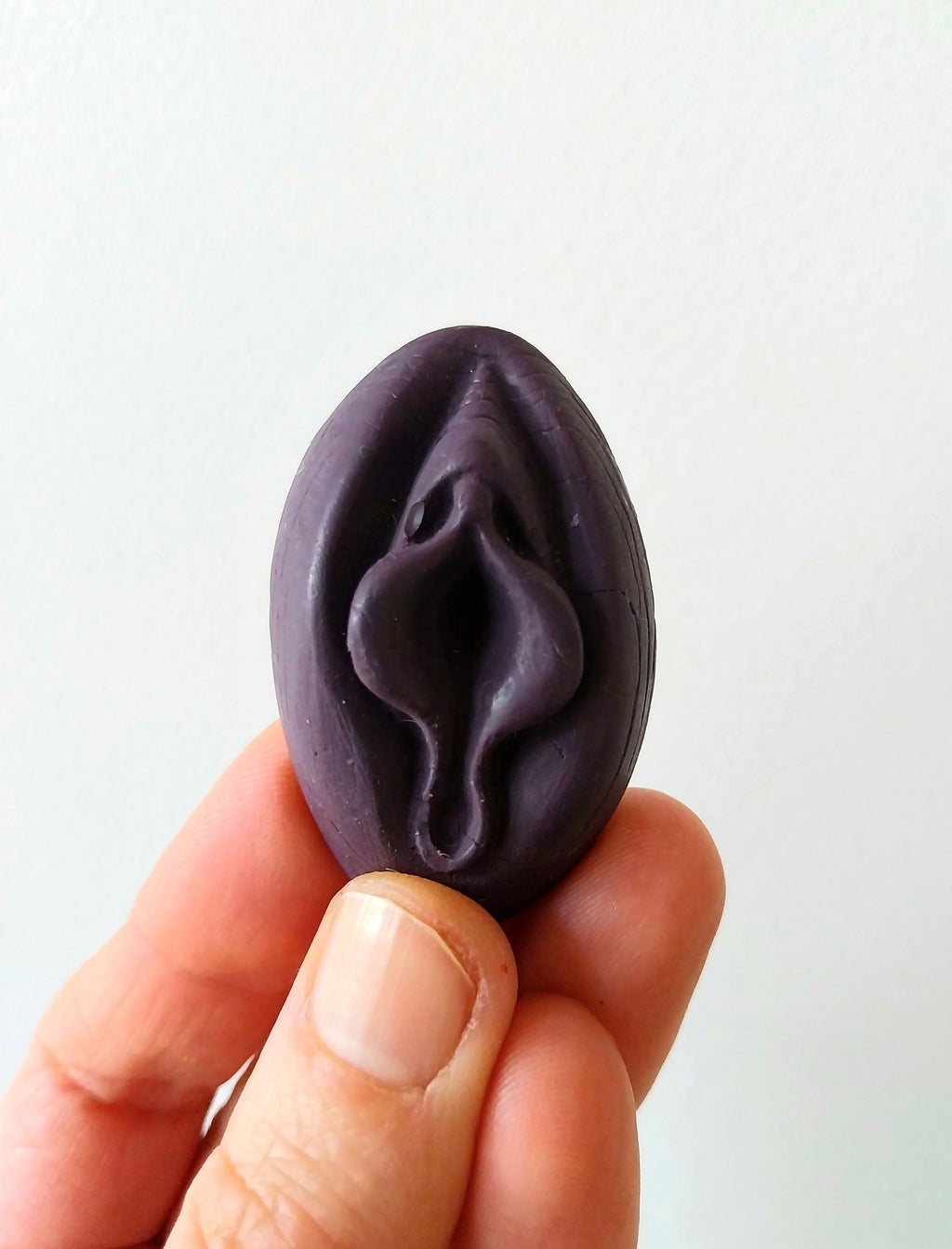 Crayon de subversion en cire végétale et pigments naturels VULVA NATURALIS, en forme de vulve, prune, vue de face.