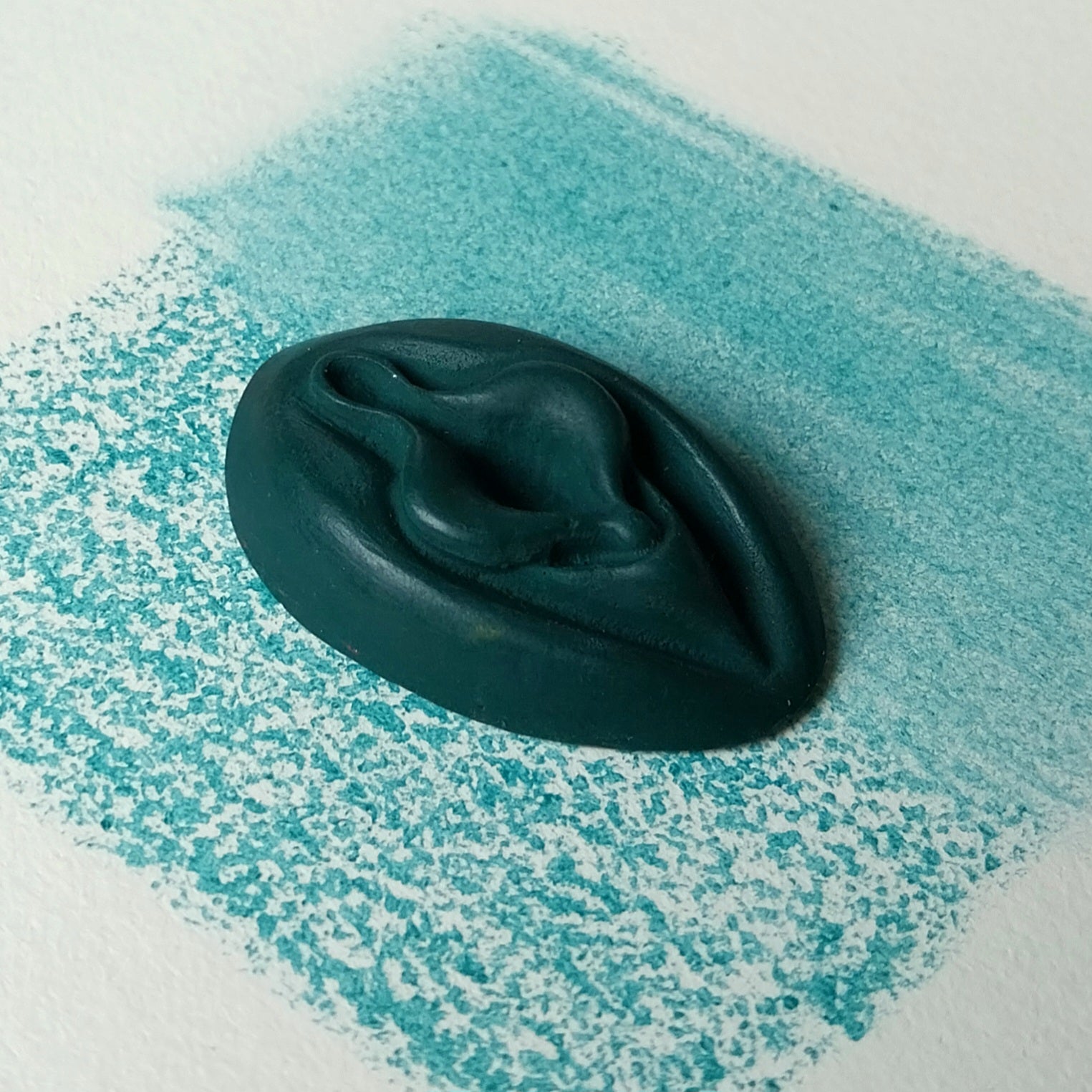 Crayon de subversion VULVA NATURALIS emeraude, vue de profil. Crayon de cire, pastel gras. Dépose de couleur sur une feuille puis estompe au doigt