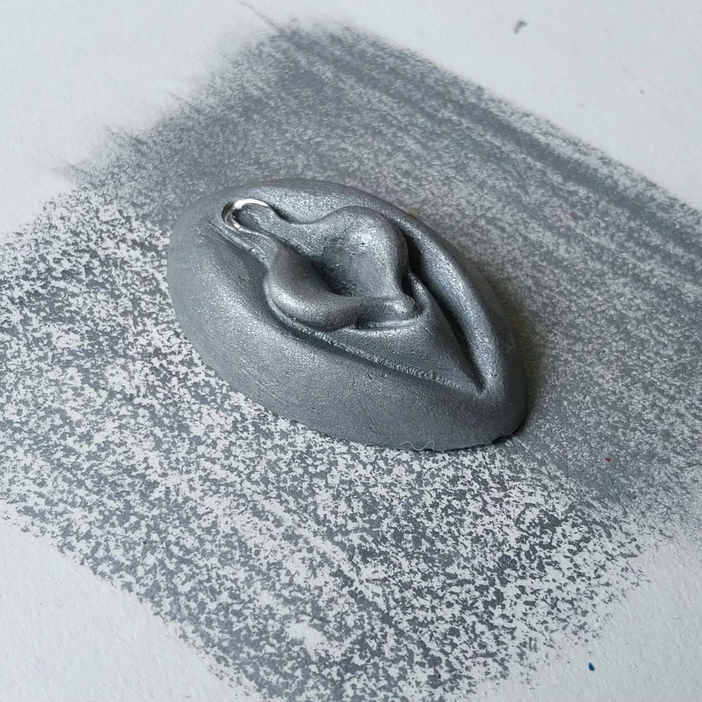 Crayon de subversion VULVA NATURALIS argenté, vue de profil. Crayon de cire, pastel gras. Dépose de couleur sur une feuille puis estompe au doigt