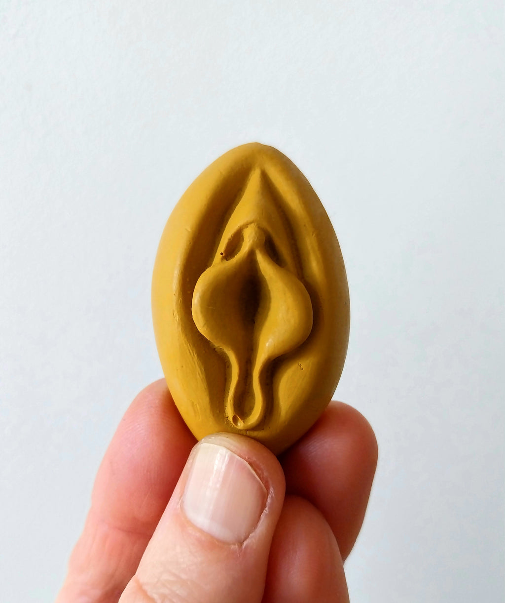 Crayon de subversion en cire végétale et pigments naturels VULVA NATURALIS, en forme de vulve, jaune, vue de face.
